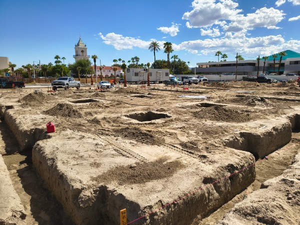 Excavated building pads and trenches at the Palm Springs Surgical Campus, with a construction trailer and downtown Palm Springs behind